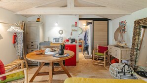 Een gezellige keuken met houten kastjes, een rode koelkast, en een eethoek met een houten tafel en stoelen.