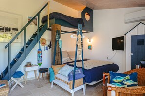 Une chambre à coucher comprenant un lit, une chaise, une petite table, un fauteuil suspendu et un escalier.