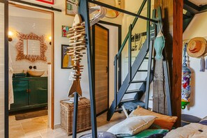 Une pièce avec un escalier, une armoire en bois, un panier en osier et un mur orné de divers objets décoratifs.