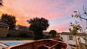 Un bote de madera en un patio trasero con piscina, árboles y una casa al fondo.