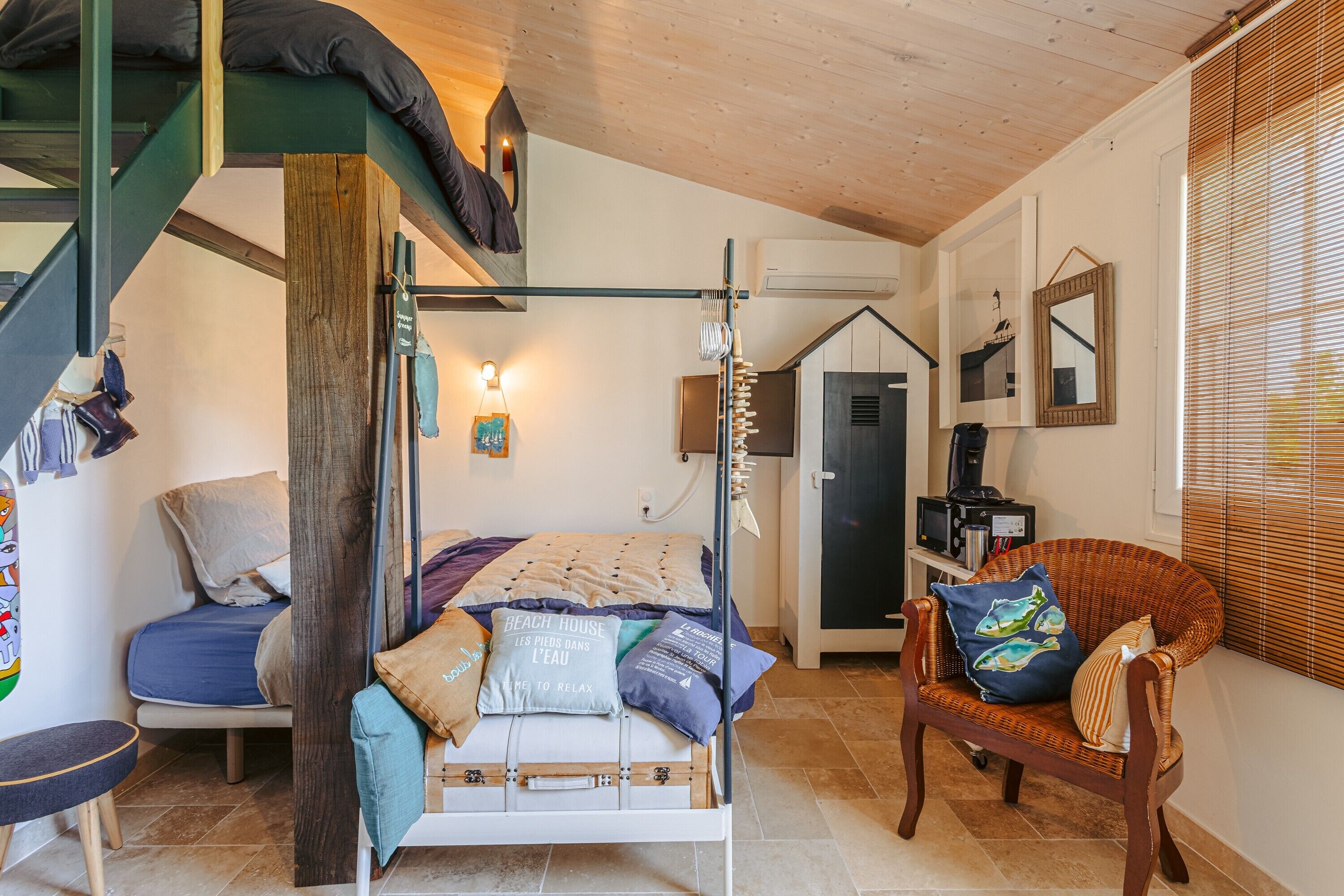 A bedroom with a bunk bed, a chair, a desk with a computer, and a window with blinds.