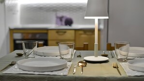 Een eettafel gedekt met borden, glazen, bestek en een lamp.