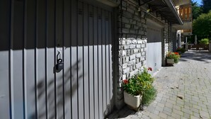 Een gebouw met een gevel van natuursteen, een metalen garagedeur en bloeiende planten in potten.