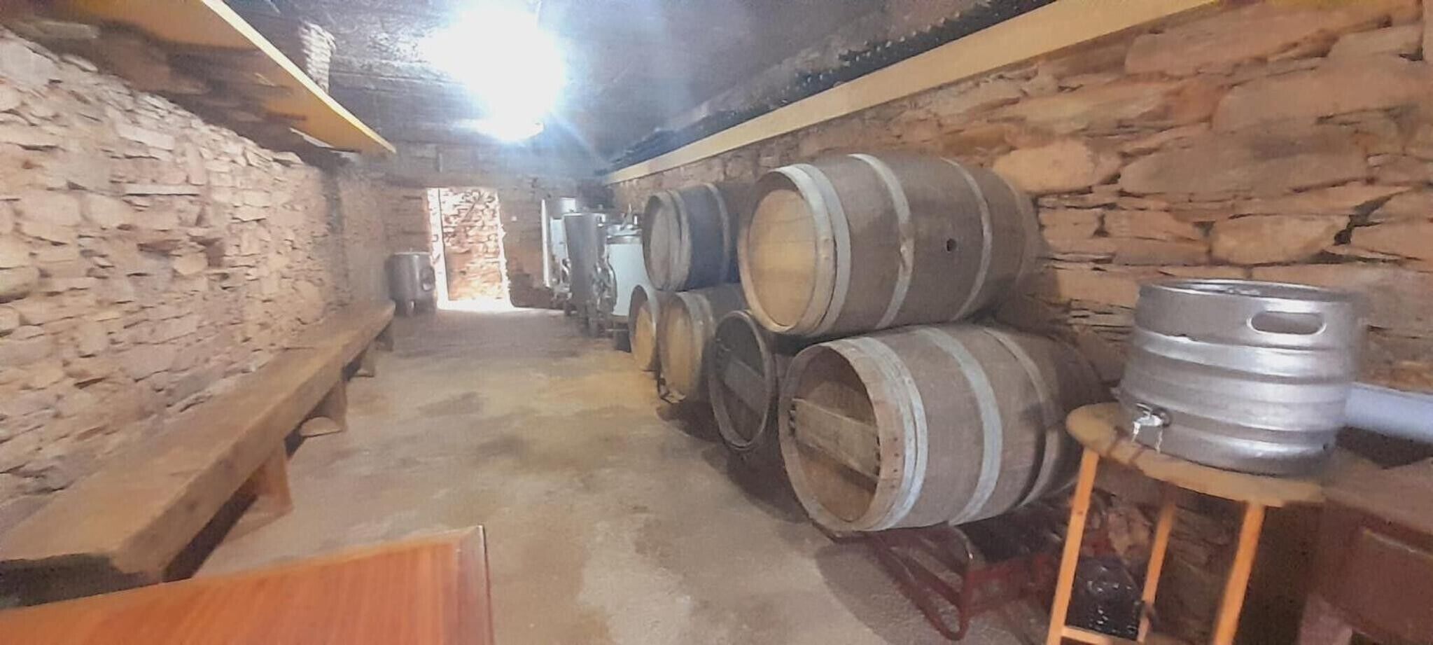 Ein Keller mit steinernen Wänden, Holzfässern und Metalleimern.