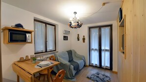 Um espaço de estar compacto com área de jantar, sofá estofado, lustre e tapete pequeno.