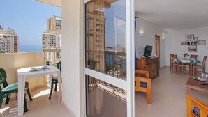 A balcony with a table and chairs, a dining area with a table and chairs, and a view of buildings and the sea. - Colmeia AL - Casa Buzz: Apartamento com Vista Mar em Armação de Pera (Unknown)