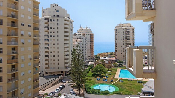 A high-rise residential building with multiple balconies, a swimming pool, and a view of the sea. - Colmeia AL - Casa Buzz: Apartamento com Vista Mar em Armação de Pera (Unknown)