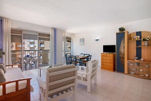 A modern living room with a bed, dining table, chairs, and a TV.