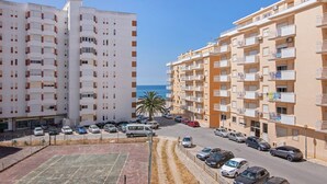 A multi-story residential building with balconies, a parking lot, and a view of the sea. - Colmeia AL - Casa Néctar (Armação de Pêra)