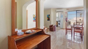 A room with a wooden bench, a large mirror, a dining table with chairs, a washing machine, and a view of the outside. - Colmeia AL - Casa Enxame (Armação de Pêra)