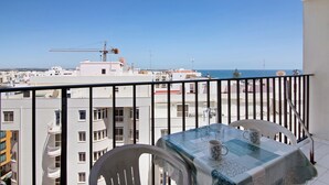 A balcony with a table and chairs, overlooking a cityscape and the sea. - Colmeia AL - Casa Enxame (Armação de Pêra)