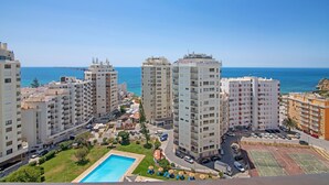 A coastal residential area with high-rise buildings, a swimming pool, tennis courts, and a clear view of the sea. - Colmeia AL - Casa Mel: Vista Mar e Conforto em Armação de Pera (Unknown)