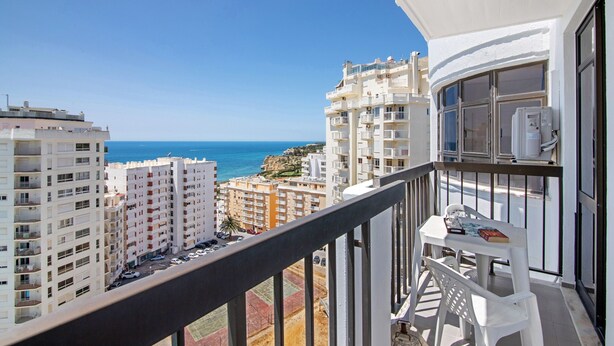 A balcony with a view of the sea, white buildings, and a table with a chair. - Colmeia AL - Casa Mel: Vista Mar e Conforto em Armação de Pera (Unknown)
