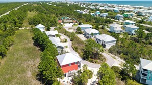 An aerial view of a coastal residential area with houses, a road, and a beach in the background. - 4 Bedroom Pet Friendly House in Fort Morgan - Free Daily Activities! (Gulf Shores)
