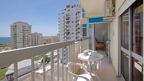 Een balkon met een tafel en stoelen, met uitzicht op een stadslandschap en de zee.