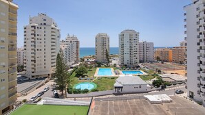 Een hoog appartementencomplex met meerdere balkons, een zwembad en uitzicht op zee.