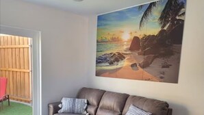 Un soggiorno con un divano in pelle marrone, un tavolino in legno e un quadro di una spiaggia.
