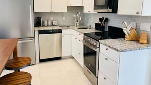 Una cucina moderna con mobili bianchi, elettrodomestici in acciaio inossidabile, un forno a microonde e un lavello.