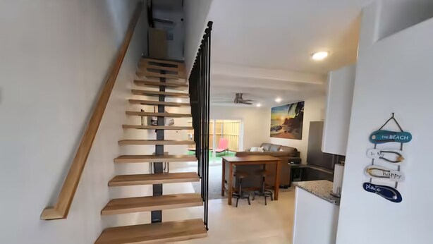 Un interno moderno con una scala in legno che conduce a una sala da pranzo e una cucina.