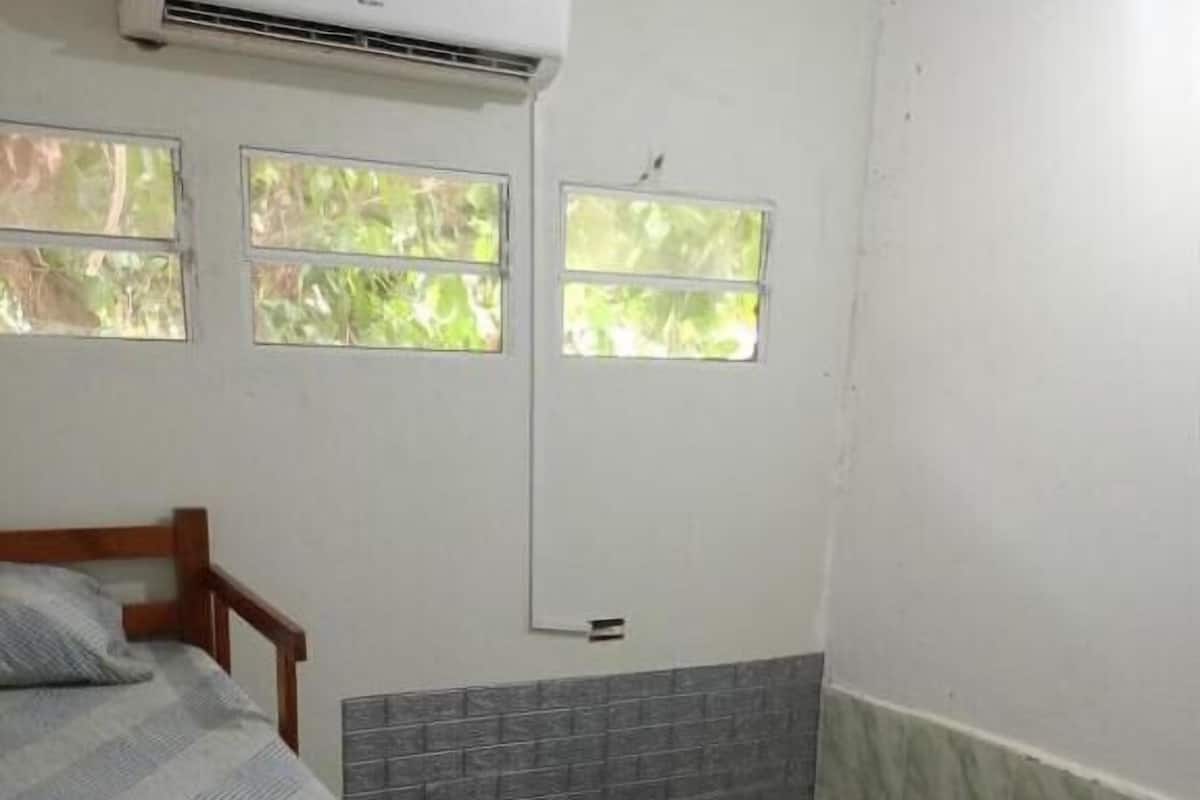 Una habitación con cama, ventana y aire acondicionado.