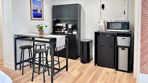 A compact kitchen with a dining area, a microwave, and a trash bin. - Studio by the Sound - King Bed • Fire Pit • EV Charger • Pet Friendly (Seattle)
