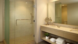 Une salle de bain moderne avec une douche à l’italienne en verre, un meuble-lavabo doté d’un grand miroir et un évier.