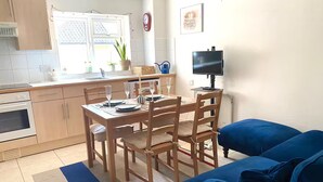 A compact living space with a kitchenette, dining area, and a blue sofa.