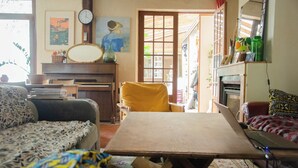 Un salon chaleureux avec un canapé, un fauteuil jaune, une table en bois et un piano.