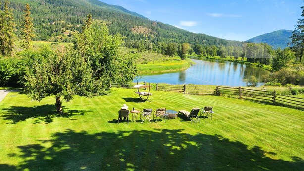 Une zone herbeuse avec un lac, des arbres et une clôture en bois.