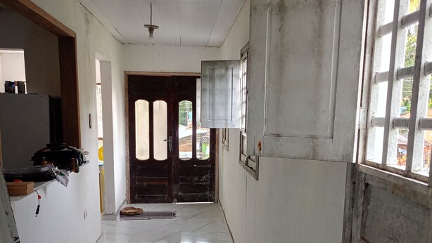 Un pasillo con piso de baldosas, una puerta al final y una ventana a la derecha.