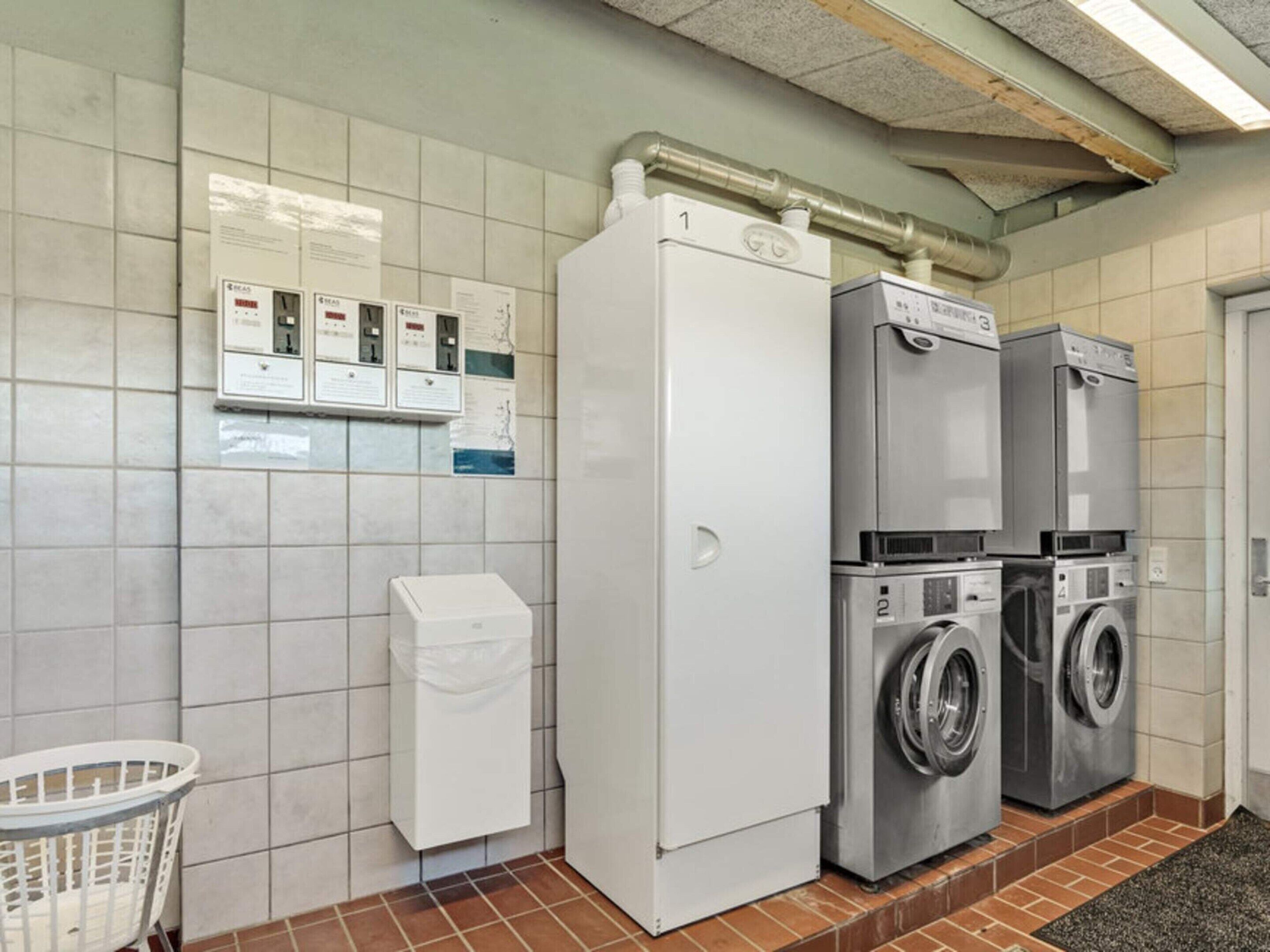 A laundry facility with a white washing machine, a dryer, and a utility panel with multiple switches.