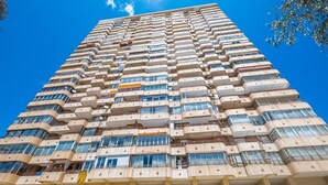 A high-rise building with multiple balconies and large windows.