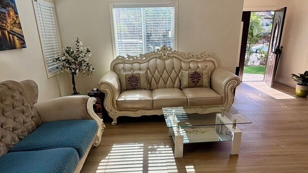 Un salón amplio con un sofá color beige, un sofá azul y una mesa de centro de vidrio.