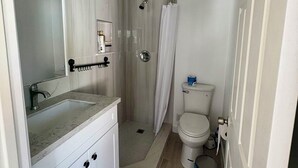 Baño con ducha, inodoro y lavabo.