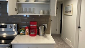 Une cuisine compacte équipée d’un four encastré, d’une machine à café et d’un moulin à café posés sur le plan de travail.