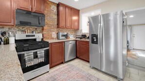 Una cocina moderna con electrodomésticos de acero inoxidable, armarios de madera y una pared de ladrillo decorativa.