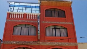 A red brick building with multiple windows and a closed metal shutter door. - Olas del titicaca backpackers  (Copacabana)