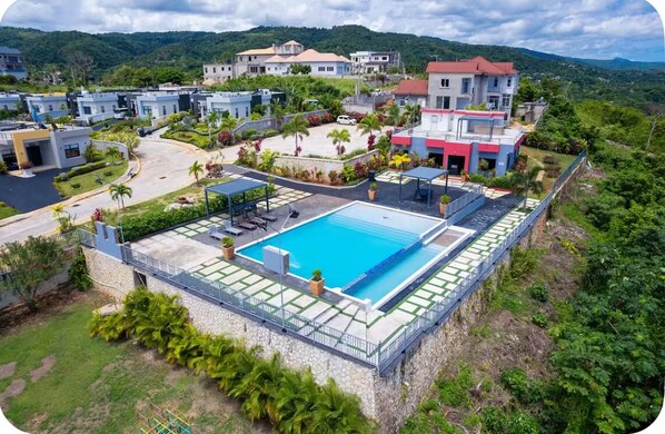 Un complexe hôtelier doté d’une piscine, de plusieurs bâtiments et d’une végétation luxuriante.