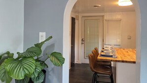 A hallway leading to a dining area with a wooden table and chairs, a potted plant, and a door. - The Beach Loft - 5 min from Whihala Beach, 
 30 min. from Chicago Navy Pier (Whiting)