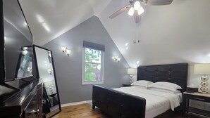 A bedroom with a bed, a dresser, a ceiling fan, and a window with a view of greenery. - The Beach Loft - 5 min from Whihala Beach, 
 30 min. from Chicago Navy Pier (Whiting)