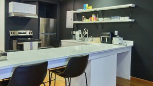 Una cocina moderna con una isla grande, electrodomésticos de acero inoxidable y taburetes negros.