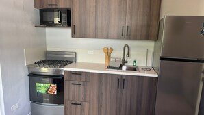 Une cuisine moderne avec des meubles en bois foncé, des appareils électroménagers en acier inoxydable et un plan de travail blanc.