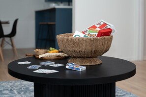 A round black table with a woven basket containing a magazine and a red box, surrounded by playing cards. - Radford Collection Three: Abilene Heights (Abilene)