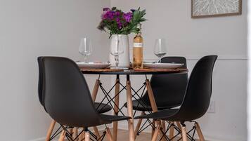 A dining table with four chairs, a vase with purple flowers, and a bottle.