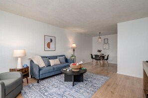 A modern living room with a sofa, coffee table, and dining area. - Radford Collection Three: Abilene Heights (Abilene)