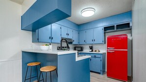 Eine Küche mit blauen Schränken, einem roten Kühlschrank und zwei hölzernen Barhocker.