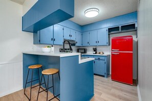 A kitchen with blue cabinets, a red refrigerator, and two wooden stools. - Radford Collection Three: Abilene Heights (Abilene)