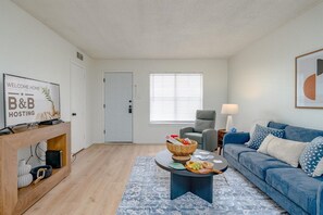 A living room with a sofa, a coffee table, a TV, and a door. - Radford Collection Three: Abilene Heights (Abilene)