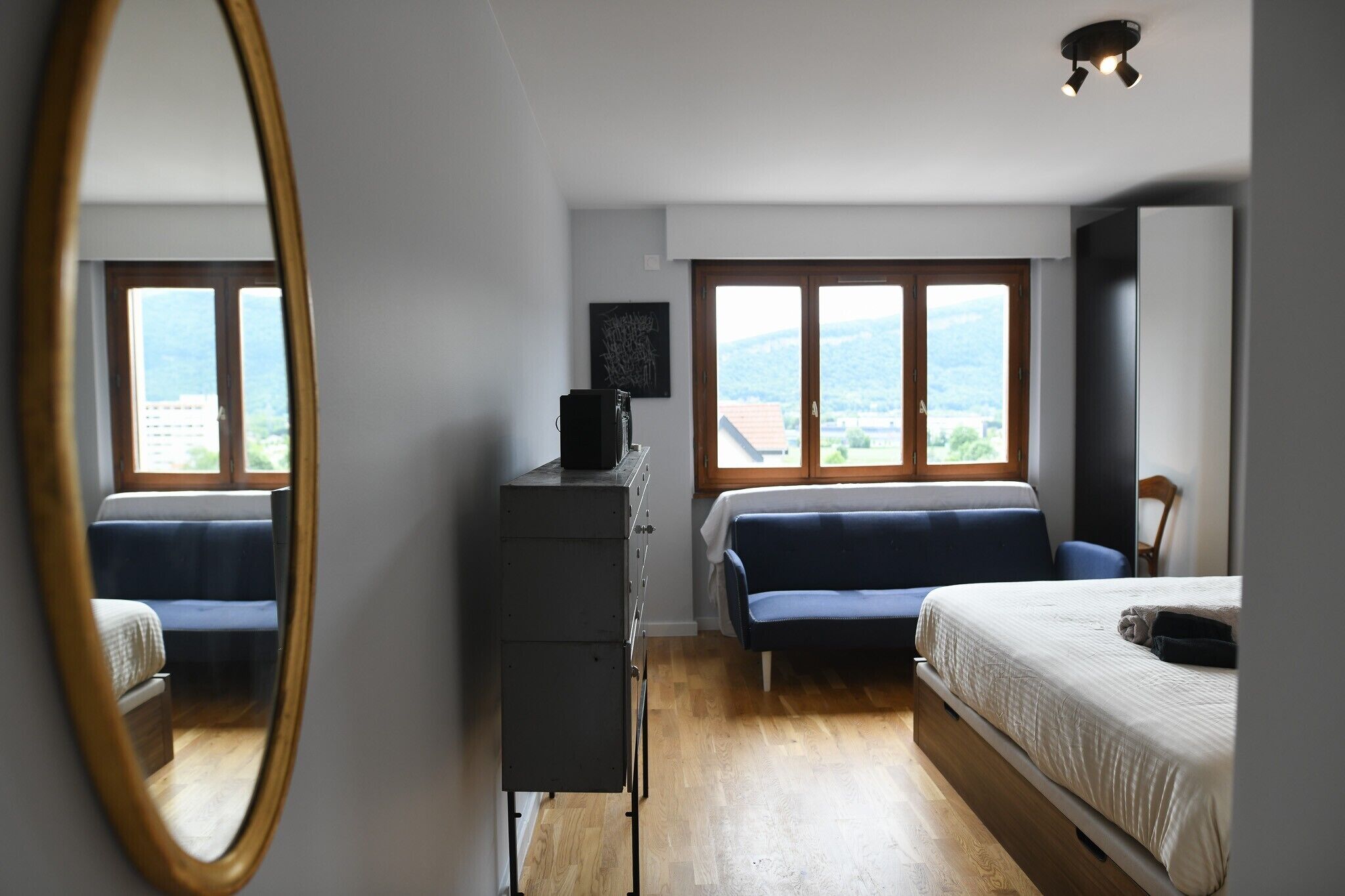 Ett sovrum med en säng, en soffa, en byrå och ett fönster med utsikt över omgivningen.