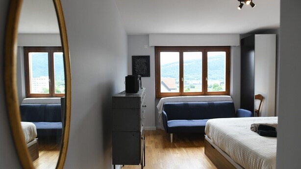 Un dormitorio con cama, sofá, cómoda y ventana con vistas al exterior.